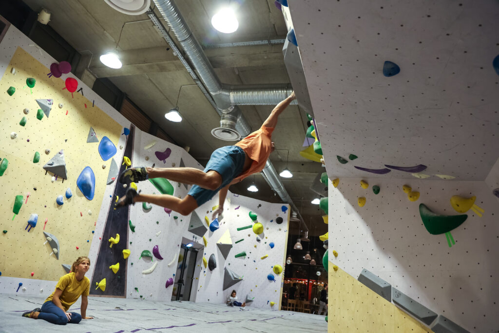 grimpeur qui chute en salle d'escalade de bloc